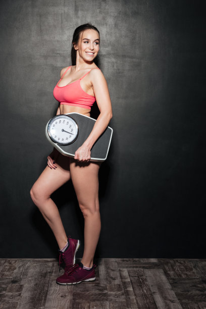 快乐的女人独自拿着体重秤图片下载