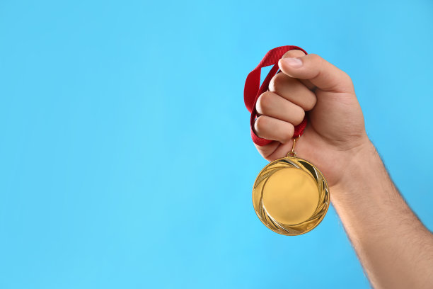 男子持有金牌在浅蓝色的背景，特写。空间设计图片下载