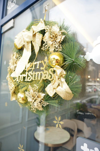 金色的圣诞花环用绿色的松枝挂在门上。选择关注圣诞圈图片下载