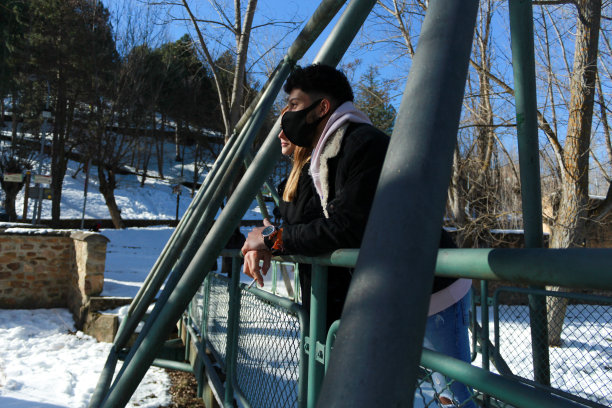 这是一对年轻夫妇的画像，一个拉丁裔和一个金发的白人在一个雪天的桥上。情人节庆祝活动。图片下载