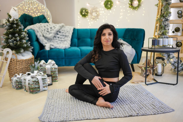 一位中年妇女在家里的沙发和圣诞树旁做瑜伽图片下载