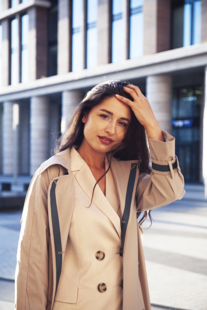年轻漂亮的黑发女人在时尚西装的商业大厦摆出开朗，生活方式的人的概念图片下载