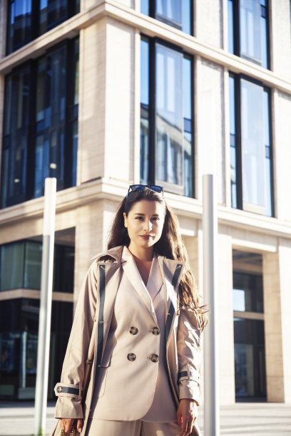 年轻漂亮的黑发女人在时尚西装的商业大厦摆出开朗，生活方式的人的概念图片下载