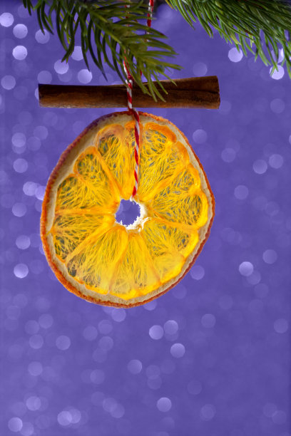 圣诞树装饰用天然材料制成。干橙片在闪亮的散景背景。2022年的颜色，非常接近。时尚的颜色概念。图片下载