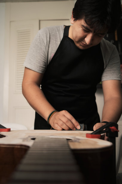 拉丁人制琴师打磨吉他的身体，为绘画做准备图片下载