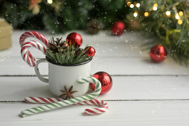 圣诞杯上有红色的气球，白色的桌子上有树枝和棒棒糖。真正的圣诞节照片。为假期做准备。出现。舒适的在家度假图片下载