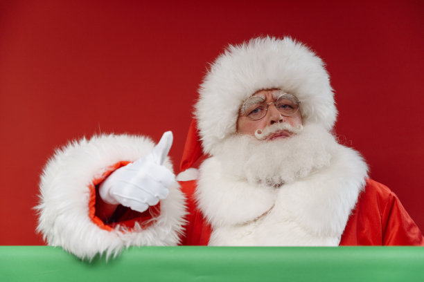 这是一个专业工作室拍摄的严肃的圣诞老人在明亮的红色背景上，在色度键上竖起大拇指图片下载