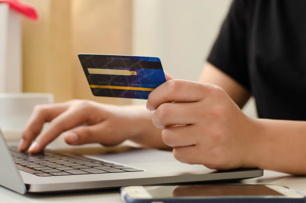 年轻的女商人拿着信用卡，在笔记本电脑上打字准备在线支付，在互联网上购物。在线支付业务金融与技术图片下载