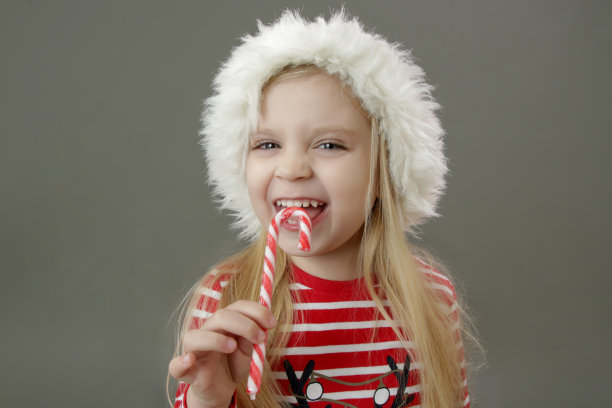 工作室肖像4岁女孩在圣诞帽拿着糖果手杖。这是假期!图片下载