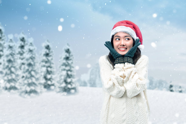 亚洲妇女与冬季手套和圣诞老人的帽子站着图片下载