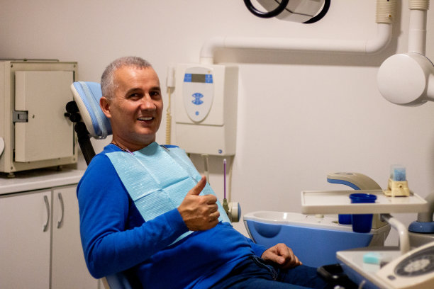 满意的病人在牙医的椅子上接受治疗后竖起大拇指微笑图片下载