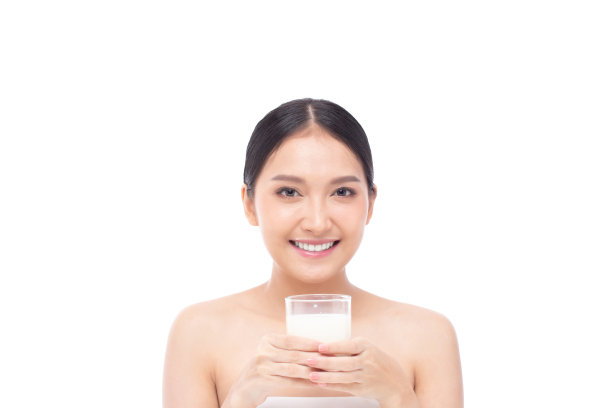 肖像的一个美丽的年轻亚洲妇女喝牛奶从玻璃孤立的白色背景在工作室拍摄，美丽的镜头。图片下载