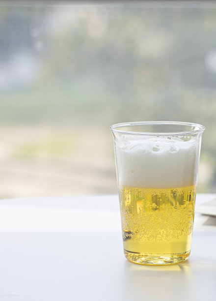 白桌子上的杯子里放着啤酒。图片下载