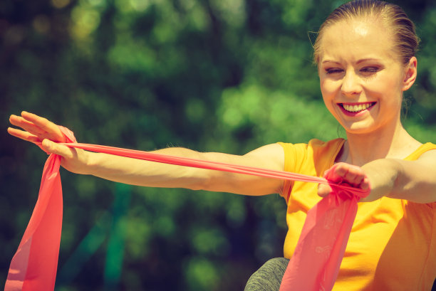 女孩在户外做运动，使用阻力贴合带。图片下载