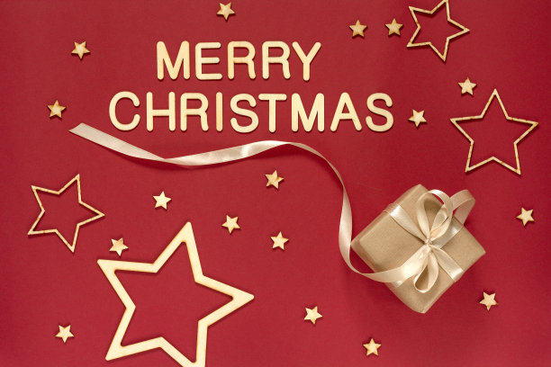 用天然纸包装的礼物，用红色(栗色)背景上的缎带包裹。用木制字母和装饰品做成的圣诞铭文。图片下载