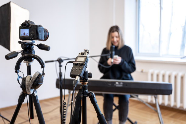 一个年轻的女孩在弹钢琴，录制视频和声音。图片下载