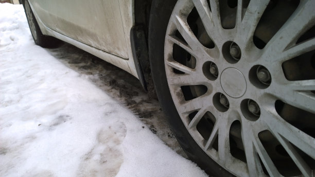 白色脏车车轮上的道路。冬天的脏乱，泥，盐，化学物质。轮胎。城市生态问题。保护和洗车概念。环境的对话。开车。汽车轮毂罩。气候变化图片下载