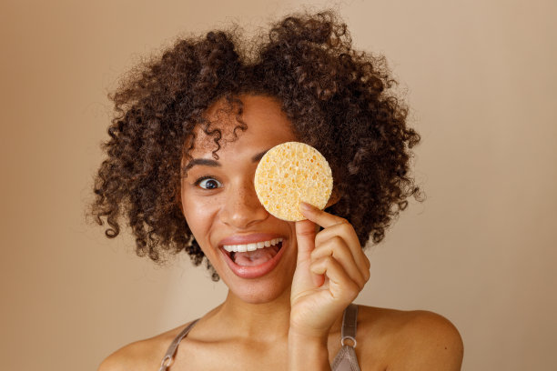 迷人的女人在米色的墙上展示化妆工具图片下载