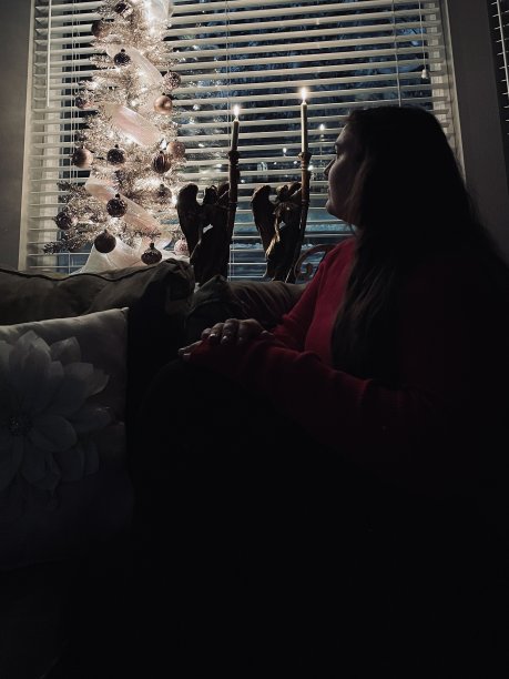 年轻女子独自坐在灯光昏暗的房间里，用圣诞灯照亮-股票照片图片下载