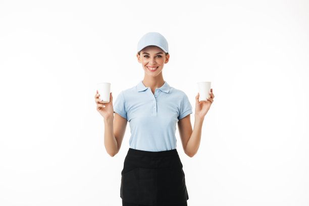 美丽的微笑女孩穿着蓝色polo t恤和帽子，手拿一次性杯子取水，在白色背景下快乐地看着相机图片下载