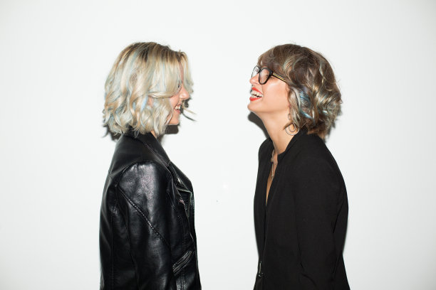 穿着黑色夹克的漂亮女孩在白色的背景下快乐地看着彼此图片下载