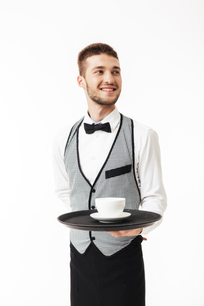 年轻快乐的服务员在制服托盘和手中的咖啡，快乐地看着旁边的白色背景图片下载