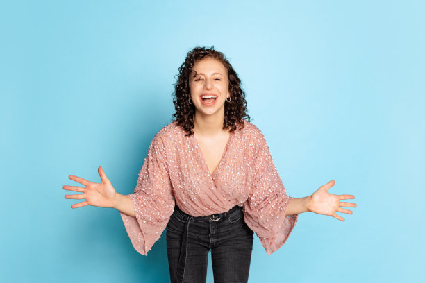 工作室拍摄的可爱的漂亮的开朗的年轻女孩，在假日服装站在与烟火孤立的蓝色背景。图片下载