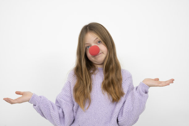 美丽的年轻女孩与红色小丑鼻子在白色背景前摆姿势图片下载