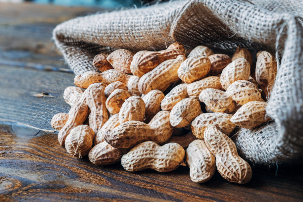 把带壳的烤干花生从袋子里倒在桌上。图片下载