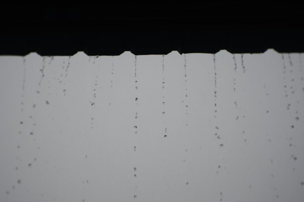 雨水从屋顶滴落下来。倾盆大雨在乡下。潮湿的气候。雨点从木屋顶的天篷上落下图片下载