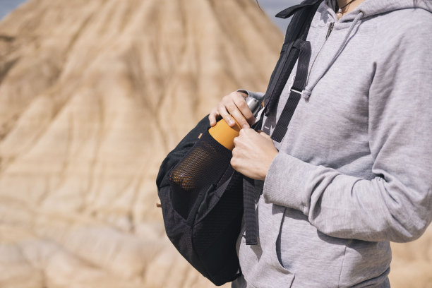 一个无法辨认的女人在她的背包里拿着一瓶水。图片下载