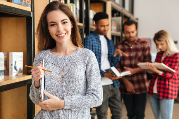 快乐的女学生站在图书馆拿着笔记本图片下载