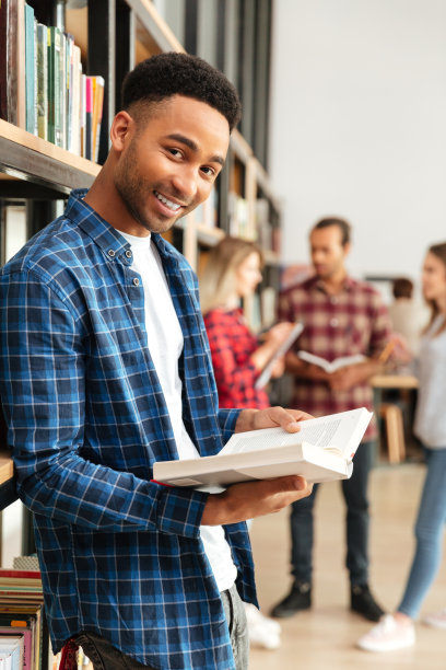 年轻快乐的非洲男子学生站在图书馆看书图片下载