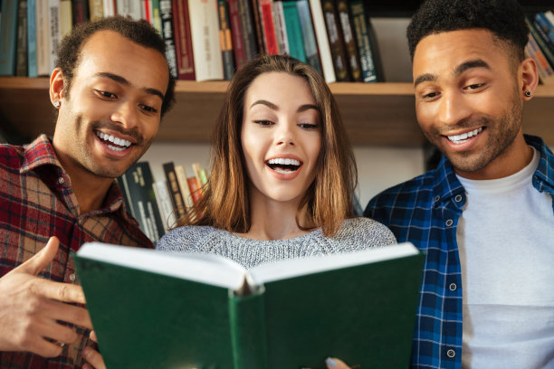 年轻快乐的学生坐在图书馆看书。图片下载