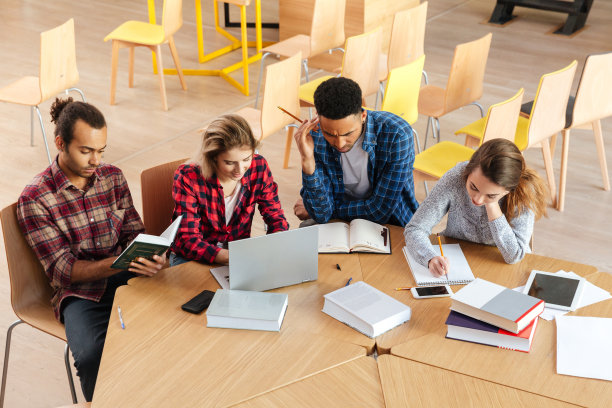 专心致志的学生坐在图书馆里用笔记本电脑看书。图片下载