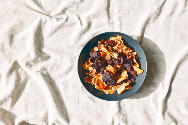 松脆的蔬菜片放在铺着亚麻布桌布的桌子上。素食点心。选择健康饮食。适当的营养。脱水蔬菜图片下载