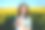 一个快乐的女学生在户外拿着书，看着相机。年轻美丽的女孩手里拿着一本《圣经》，背景是田野里的黄花。图片下载