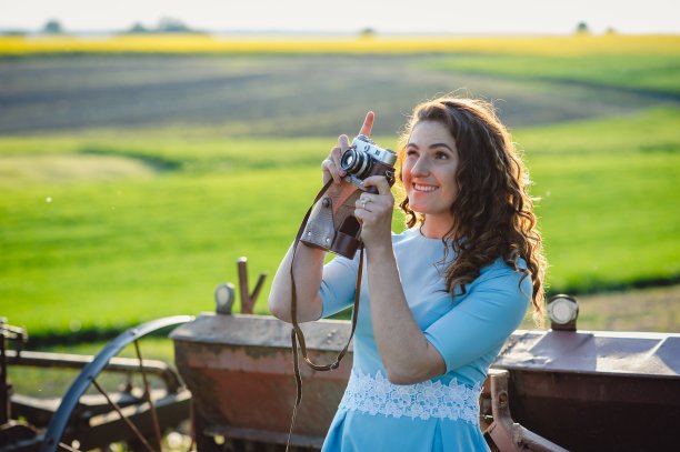 近肖像的微笑美丽的女孩拍照复古相机。一个穿着蓝色连衣裙的漂亮女孩正微笑着，手里拿着一台复古相机。小屋里拿着相机的女孩图片下载