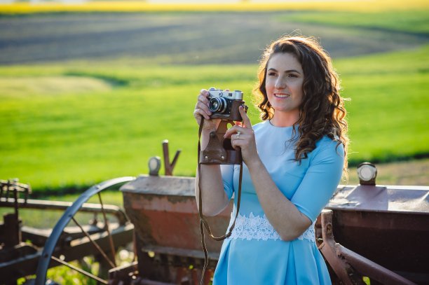 近肖像的微笑美丽的女孩拍照复古相机。一个穿着蓝色连衣裙的漂亮女孩正微笑着，手里拿着一台复古相机。小屋里拿着相机的女孩图片下载