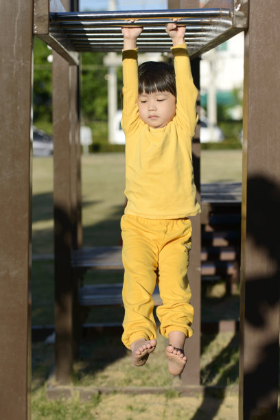 小亚洲男孩攀登猴酒吧在户外游乐场在早上图片下载