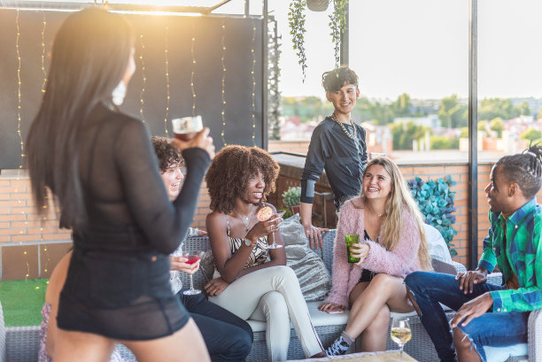快乐的多民族朋友在阳台上玩和喝酒图片下载