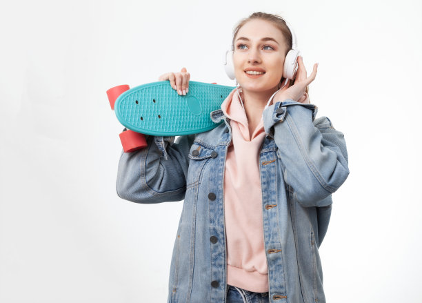 年轻的白人欢快的嬉皮士女人，穿着牛仔衣服，头戴耳机，在白色背景下听音乐图片下载