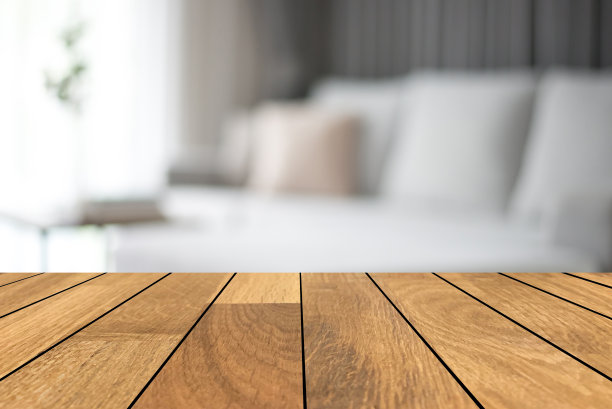 空的木制桌面前面模糊的室内舒适的角落在客厅与沙发和枕头的背景。可用于展示或蒙太奇您的产品。为产品展示制作模型。图片下载