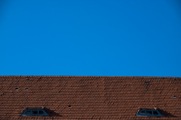 瓷砖屋顶，烟囱，白墙，蓝天为背景图片下载