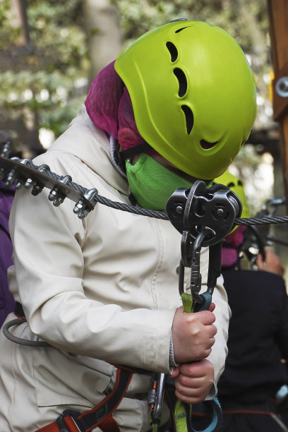 儿童戴上头盔、面罩及装备，在攀登绳索公园前先听教练讲解。图片下载