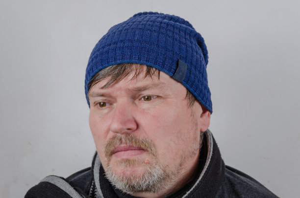 一个悲伤的成年男子的肖像靠在浅色的墙上。成年男性在图片下载