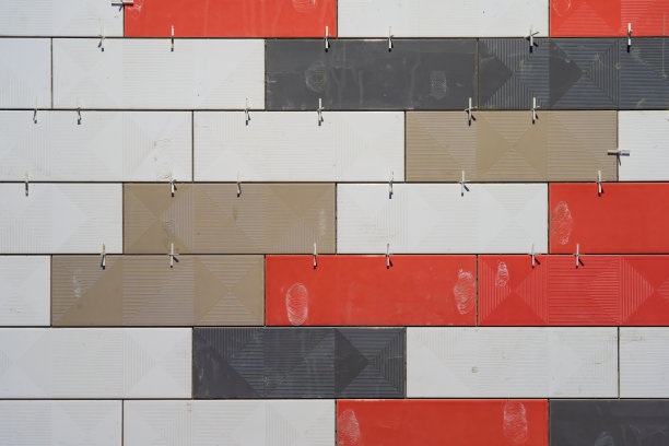 在建造时，墙壁的碎片与不同颜色的彩色瓷砖。可提供塑料配件和施工泥浆。背景。纹理。图片下载
