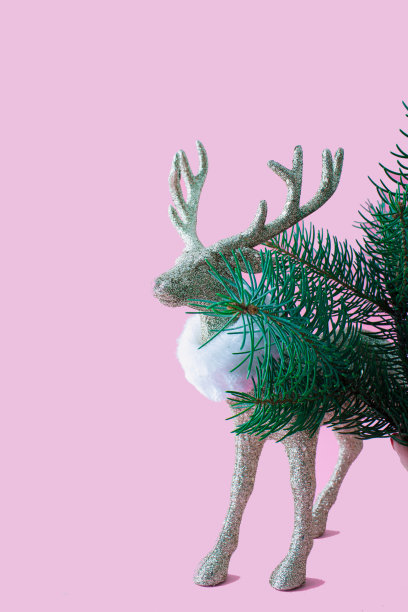 有大鹿角和白色围巾的驯鹿在紫罗兰色的背景上与圣诞树。圣诞节或新年的最小概念。图片下载