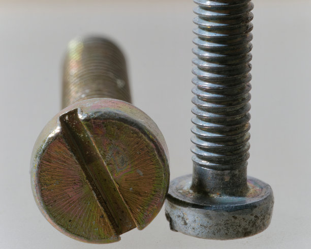 一个生锈的金银螺丝在白色背景上的特写照片图片下载