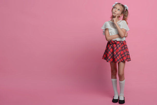 可爱的女学生穿着红色的裙子，背着粉红色的背包。情感上的肖像。回到学校图片下载